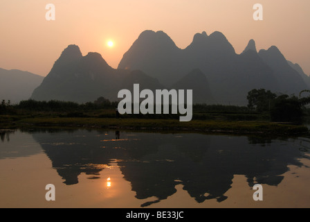 Karst-Klippen und Reisfelder in der Abendsonne zur Erntezeit im Yulong River in die steinige Karstlandschaft spiegeln Stockfoto