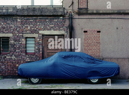 Geparktes Auto in einem tristen Hinterhof mit mit einer Plane bedeckt Autoabdeckung, Duisburg, Nordrhein-Westfalen, Deutschland, Europa Stockfoto