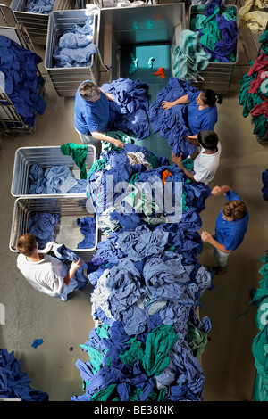 Grüne und blaue Krankenhaus Kleidung wird sortiert nach Typ und Farbe nach dem Waschen in einer industriellen Wäscherei, Textil-Mietdienst Stockfoto
