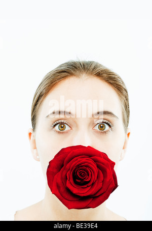 Porträt der jungen Frau mit einer Rose im Mund Stockfoto