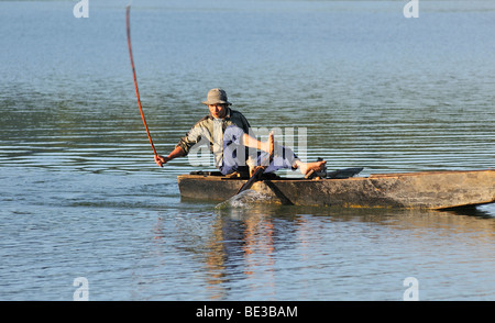 Fischer in einem hölzernen Angeln Boot mit der traditionellen Stick-Schlag-Methode, Tuyen Lam See, Dalat, Hue, Vietnam, Stockfoto