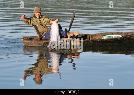 Fischer in einem Holzboot zieht ein Netz auf Tuyen Lam See, Dalat, Hue, Vietnam, Asien Stockfoto