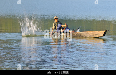 Fischer in einem hölzernen Angeln Boot mit der traditionellen Stick-Schlag-Methode, Tuyen Lam See, Dalat, Hue, Vietnam, Stockfoto