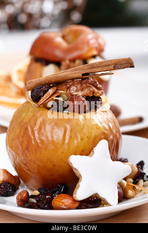 Bratapfel mit Rosinen, Nüssen, Marzipan, Zimtstange und Zimtstern, Zimt Biskuit, in festlicher Atmosphäre Stockfoto