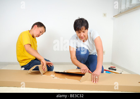 Mutter und Sohn, Montage von Möbeln, öffnen der Verpackung Stockfoto