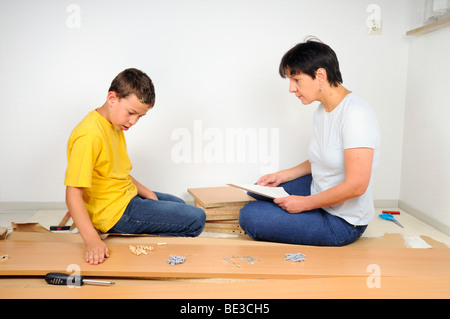 Mutter und Sohn, die Montage von Möbeln, die Anweisungen zu lesen Stockfoto