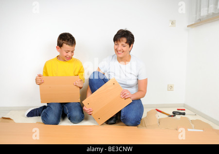 Mutter und Sohn, Montage von Möbeln, die Regale Auspacken Stockfoto