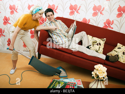 Retro-1960er Jahre paar, Mann auf Sofa, Frau saugen Stockfoto