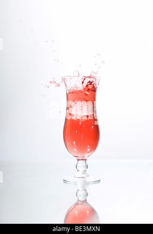 Eiswürfel in ein Glas roter Flüssigkeit, Saft, cocktail fallen Stockfoto