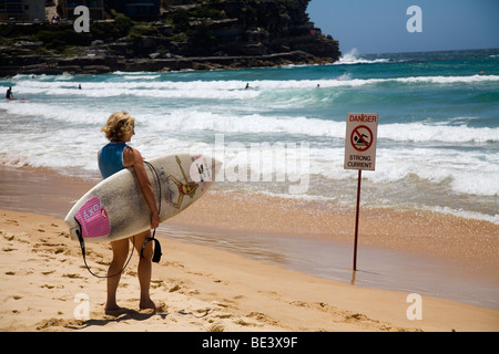 Eine Surferin blickt auf die Wellen am Manly Beach. Sydney, New South Wales, Australien Stockfoto