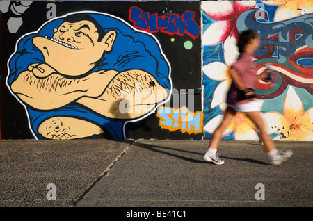 Ein Spaziergänger auf der Promenade am Bondi Beach, mit den Wänden mit Streetart Wandmalereien verziert. Sydney, New South Wales, Australien Stockfoto