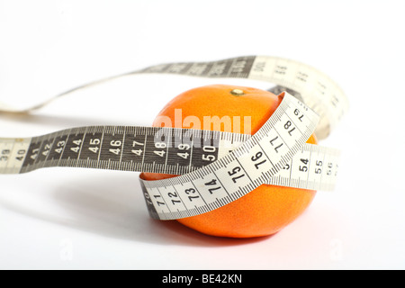 Eine Schneiderin Maßband, mit metrischen Maßen, mit einer Mandarine, als Symbol für eine gesunde Ernährung mit Obst Stockfoto