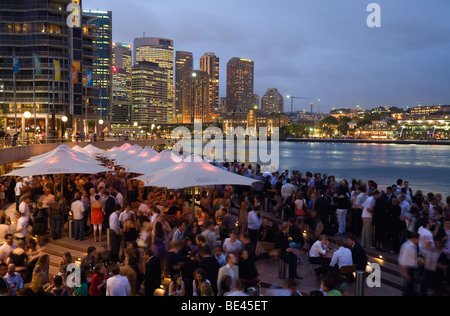 Menschenmengen füllen die Opera Bar am Hafen von Sydney mit Circular Quay im Hintergrund.  Sydney, New South Wales, Australien Stockfoto