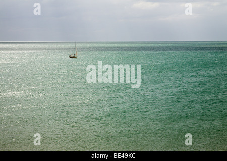 Eine einsame Yacht segelt auf einem blau-grüne Meer. Stockfoto