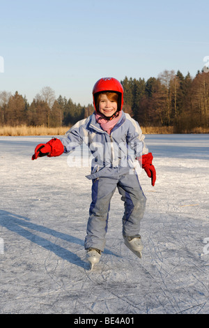 Mädchen das Tragen eines Helmes Eislaufen auf einem kleinen See Stockfoto