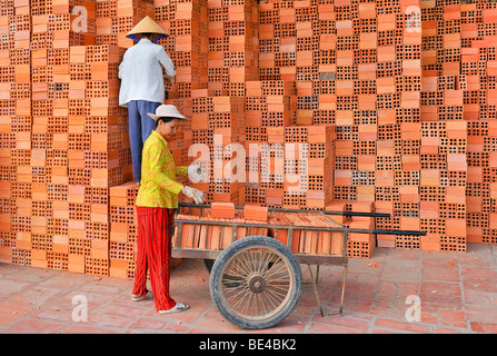 Zwei Arbeiter, Frauen tragen traditionelle vietnamesische Stroh Hüte Stapeln Ziegel in einer Ziegelfabrik Vinh Long, Mekong-Delta, Filmkunst Stockfoto