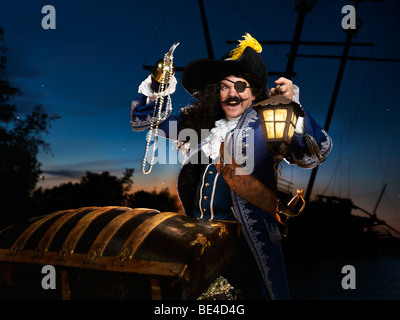 Lizenz erhältlich unter MaximImages.com - Pirat mit Laterne, die eine Schatztruhe öffnet Stockfoto