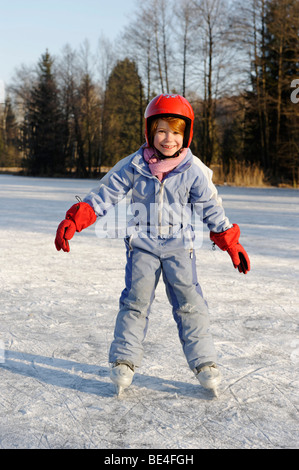 Mädchen das Tragen eines Helmes Eislaufen auf einem kleinen See Stockfoto