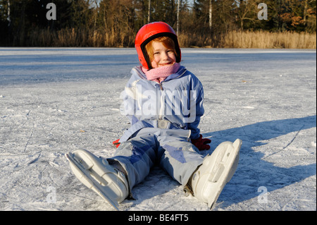 Mädchen das Tragen eines Helmes Eislaufen auf einem kleinen See Stockfoto