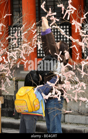 Japanische Mädchen und ihre Mutter verknoten, Gebete und Wünsche, die Sträucher in der Shinto-Heian-Schrein, Kyoto, Japan, Asien Stockfoto