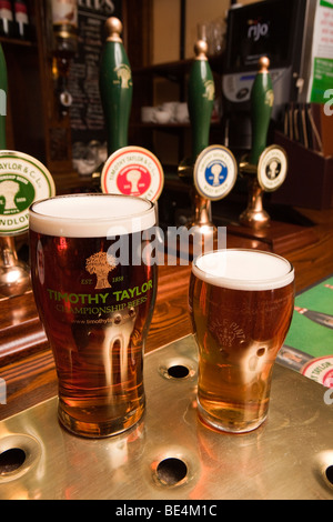 Großbritannien, England, Yorkshire, Haworth, Fleece Inn Pint und die Hälfte der lokal Timothy Taylors Bier gebraut auf Bar Stockfoto