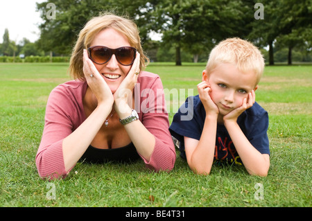 Horizontale Nahaufnahme Portrait eines jungen und seiner Mutter zusammen mit ihren Kopf in ihre Hände auf dem Rasen in einem Park liegen. Stockfoto