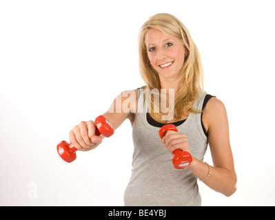 Junge blonde Frau trägt Sportbekleidung und hält Hanteln Stockfoto