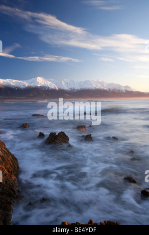 Wellen auf den Felsen und früh Licht auf Seaward Kaikoura Range, Kaikoura, Südinsel, Neuseeland Stockfoto