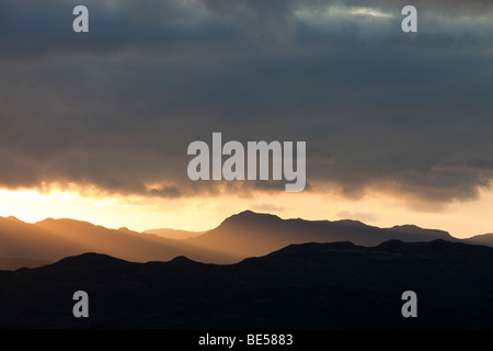 Wellen des Lichts von der untergehenden Sonne über dem Lake District Berge, Cumbria, UK Stockfoto