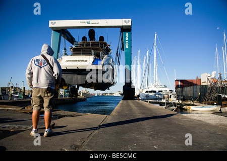 Ein Operator führt einen Travel Lift marine Kran eine Motoryacht aus dem Wasser auf der Werft von Newport in Newport schleppen Stockfoto