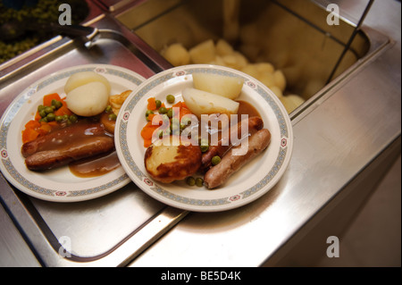 Schule-Abendessen - Wurst-Gemüse und Kartoffeln - serviert auf Platten in einer Grundschule Kantine Halle, Wales UK Stockfoto