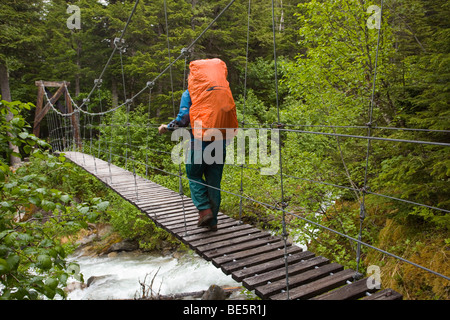 Weibliche Wanderer mit Rucksack Überquerung Hängebrücke über Taja Fluss, nahe der historischen Canyon City, Pazifischer Nordwesten Küste Rai Stockfoto