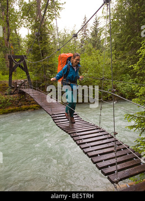 Frau, weibliche Wanderer mit Rucksack Überquerung Hängebrücke über Taja Fluss, nahe der historischen Canyon City, Pacific Northwest Co Stockfoto