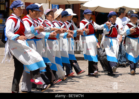 Ältere Frauen der Naxi-Minderheit in Naxi Kleid mit Mao Hut Durchführung öffentlicher Volkstanz, Lijiang, Yunnan, Süd-China, China, Stockfoto