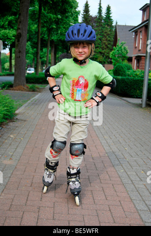 Mädchen mit Inline-Skates, ist 5 Jahre, durch einen Helm und Arm und Knie-Protektoren geschützt. Stockfoto