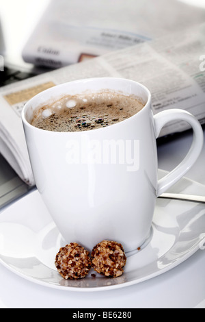 Tasse Kaffee mit Mini-Gebäck und Zeitung in den Rücken Stockfoto