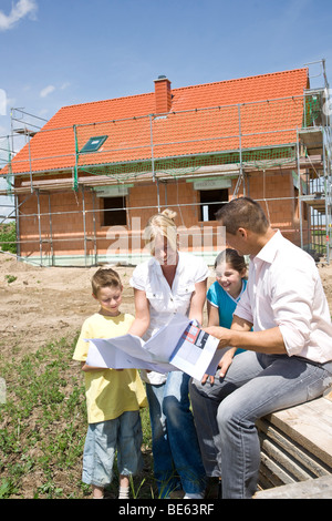Familie den Bauplan vor ihr zukünftiges Haus diskutieren Stockfoto