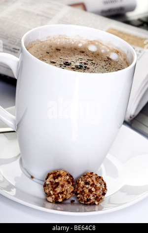 Tasse Kaffee mit Mini-Gebäck und Zeitung in den Rücken Stockfoto