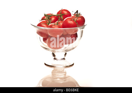 Bio-Tomaten auf dem Rebstock in eine Glasschüssel gegen ein weißes Studio-Ausschnitt-Hintergrund Stockfoto