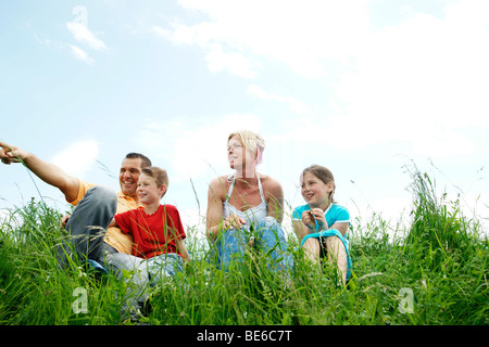 Familie sitzen auf einer Wiese, Blick in die Ferne Stockfoto