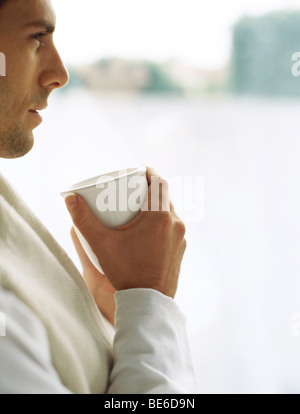 Mann halten Tasse Kaffee, dachte auf der Suche nach in Stockfoto