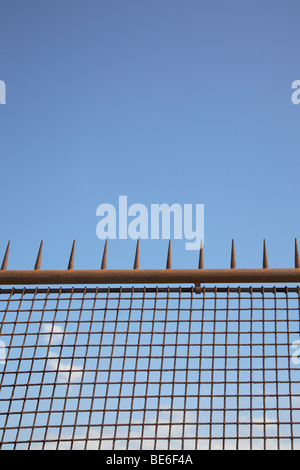 Große, rostige Eisenzaun mit Spikes vor blauem Himmel. Stockfoto