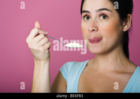 Frau Verkostung Löffel voll Eis, Lippen lecken Stockfoto