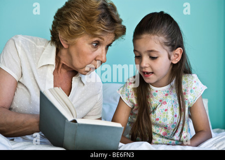 Kleines Mädchen Buch mit Großmutter Stockfoto