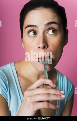 Frau lecken Löffel, wegschauen Stockfoto