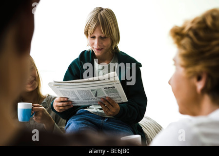 Jungen lesen Zeitung, Familienmitglieder im Vordergrund Stockfoto