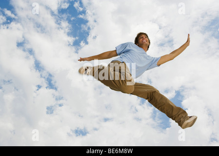 Junger Mann springt freudig in der Luft, niedrigen Winkel Ansicht Stockfoto