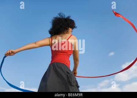 Junge Frau drehte sich um mit Bändern im freien Stockfoto