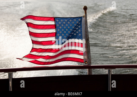 Vom Wind verwehten US-Flagge in Motorboote wecken. Stockfoto