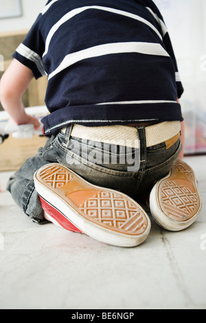 Kleiner Junge kniend am Boden, Rückansicht Stockfoto